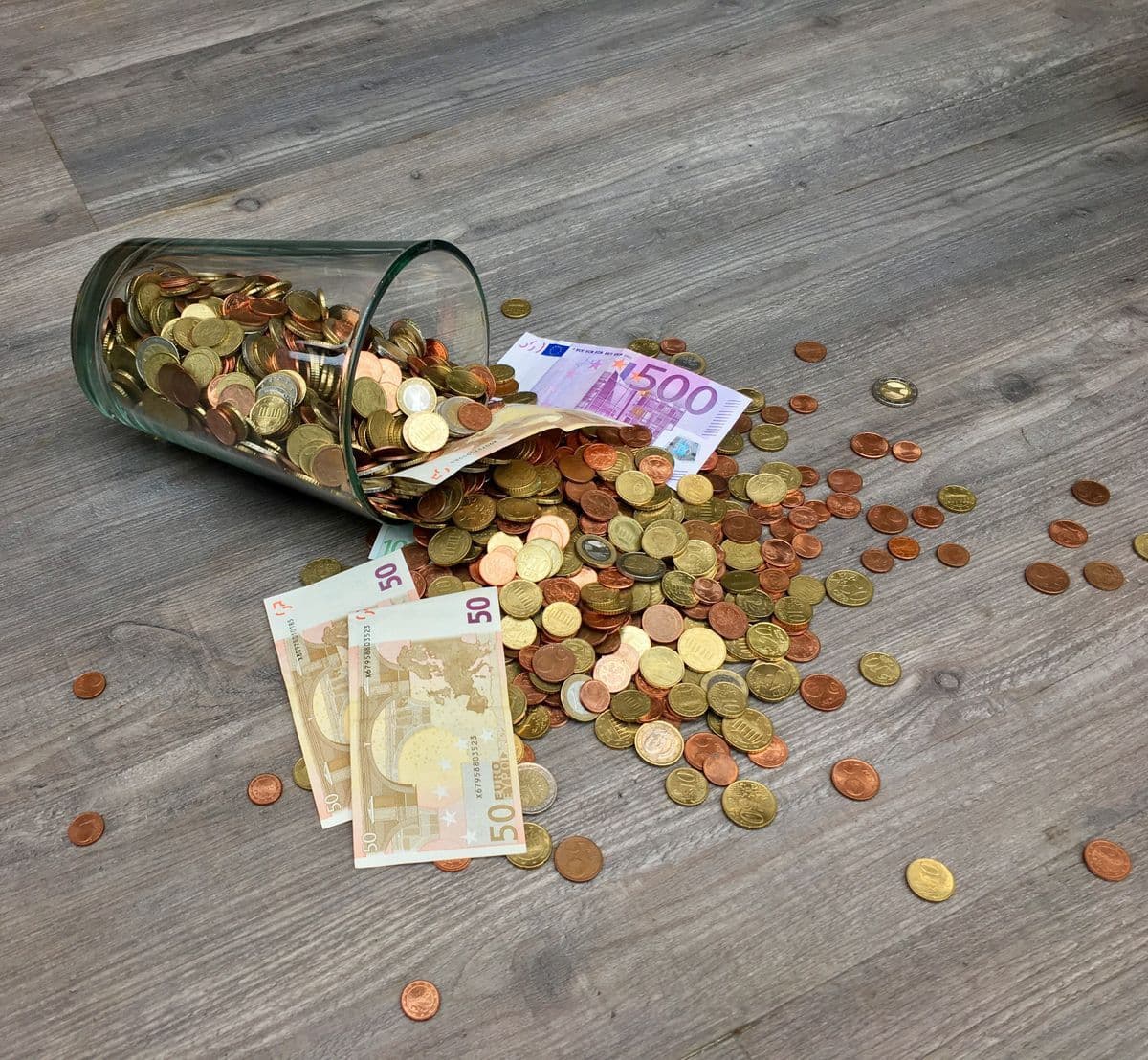 Hucha de cristal con monedas y billetes de euro